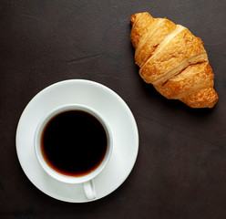 coffee and croissants on wooden cutting board, on the background concrete
