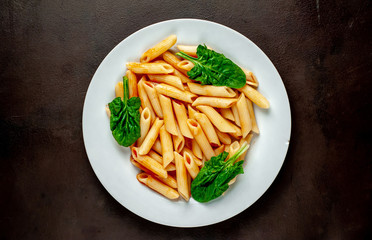 Penne pasta in tomato sauce on concrete background