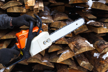 A man keeps the saw near the logs at the open air