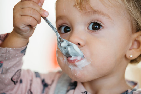 Portrait of baby girl eating yogurt, close-up