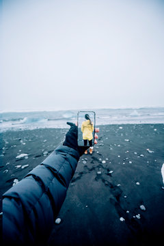 D montage of man taking smartphone picture of Iceland's landscape and woman wearing yellow raincoat