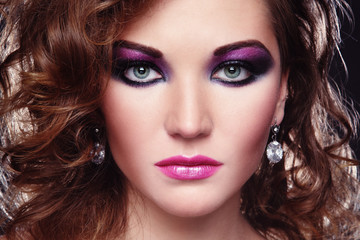 Young beautiful girl with glowing colorful disco make-up and curly hair