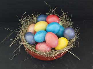 Easter eggs in a nest with hay on a black chalk background