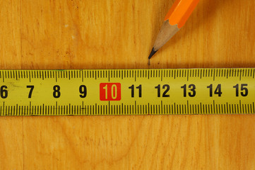 Pencil marking of a wooden cutting board with a metal measuring tape.