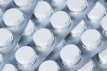 White pills in silver packaging on a white background.