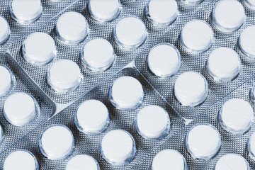 White pills in silver packaging on a white background.