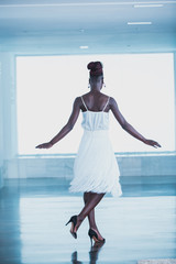 Attractive black woman wearing white fringed dress dancing on a dance floor