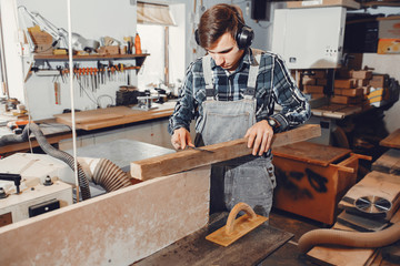 A man carves a tree. The carpenter works in a studio. An engineer provides a tree shape
