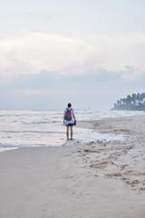 A young man walks on the beach and takes pictures.