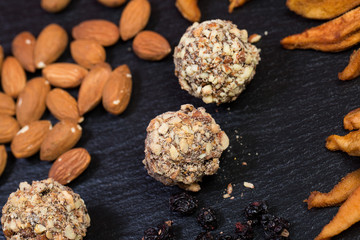 Obraz na płótnie Canvas Theme is a sweet dessert made from natural products without sugar. Macro close up closeup dessert sweet candy round ball handmade truffle dried fruit set of almonds dried pear and honey