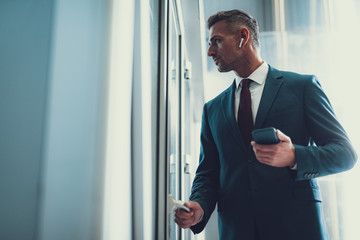 Man with telephone looking through glass door in office