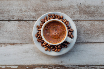 Turkish or Greek Hot Coffee on the white rustic wooden table with spilled coffee beans. This is traditional tasty refreshment greek or turkish coffee from greek or turkish cuisine culture