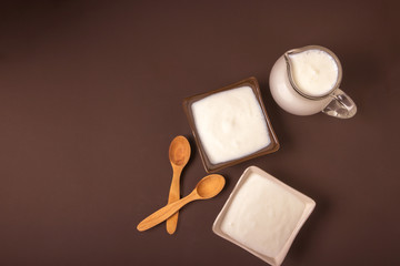 Homemade yogurt in ceramic square bowls, a jug brim full of yogurt behind the bowls. Healthy food from yogurt concept. Top view