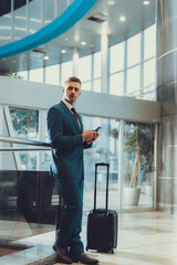 Man with suitcase using telephone and waiting departure on trip