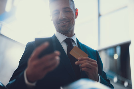 Smiling Man Holding Bank Card And Telephone In Hands