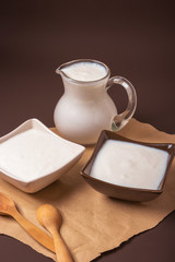 Homemade yogurt in ceramic square bowls, a jug brim full of yogurt behind the bowls. Healthy food from yogurt concept