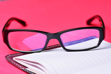 Items freelancer on a red background. Glasses and notebook