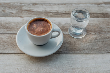 Turkish or Greek Hot Coffee on the white rustic wooden table with spilled coffee beans. This is traditional tasty refreshment greek or turkish coffee from greek or turkish cuisine culture