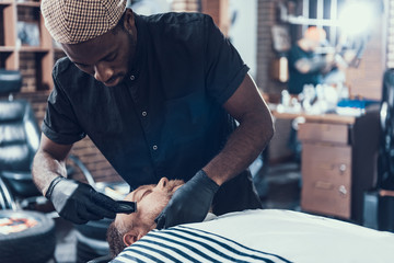 Attractive man shaving customer in barber shop