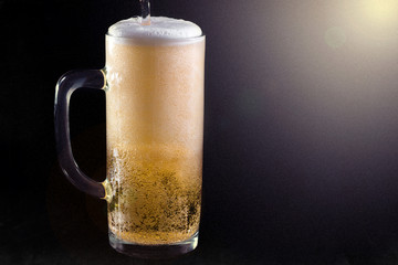 Full mug of filtered light beer on a dark background