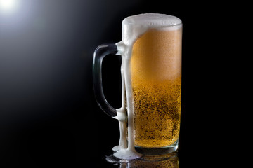 Cold beers with foam drops on dark background. Pouring foam on the glass
