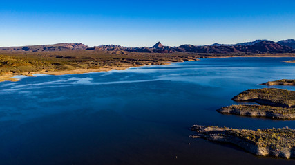 Fototapeta premium Aerial, drone view of Alamo Lake, Arizona in the remote desert near Wenden with vivid blue water and sky with Alamo Dam