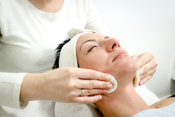 Fototapeta na wymiar beautician worker gently massages face of female costumer in beauty salon