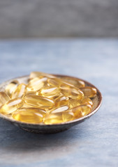 Fish oil capsules with omega 3 on rustic background. 