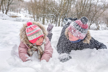 Children are playing snowballs lying in the snow, a close-up.