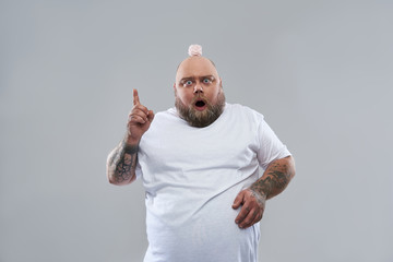 Expressive fat man pointing his finger up while standing with marshmallow