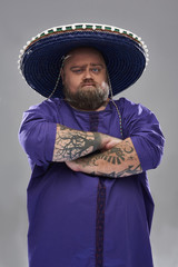 Waist up of fat man wearing sombrero and standing with crossed arms