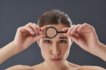 Pretty young woman using loupe to checking wrinkles