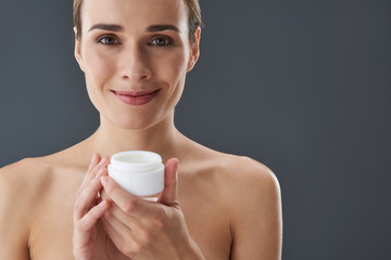 Pretty  young woman with cream jar in hands