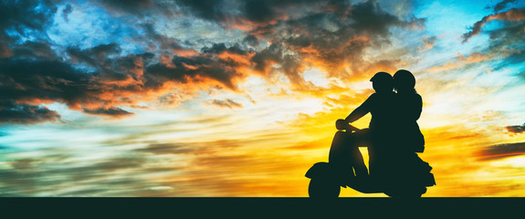Girl and boy riding a scooter at sunset © ginettigino