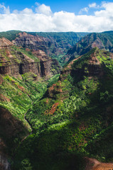 Beautiful dark green canyon, mountain range and cloudy sky in Kauai, US