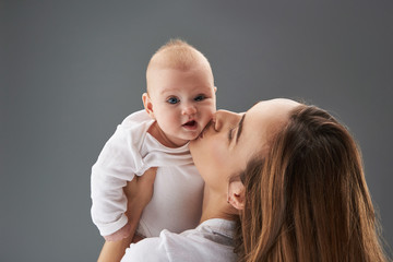 Lovely mama kissing funny baby in cheek