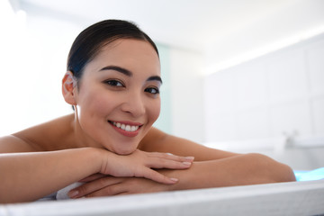 Obraz na płótnie Canvas Smiling asian lady laying on massage table