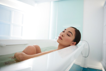 Asian lady close eyes while enjoying spa bath