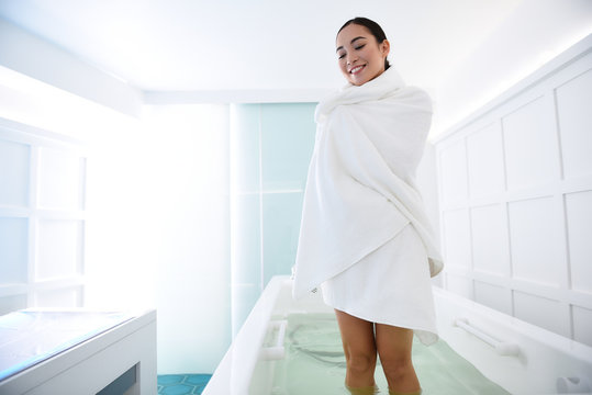 Smiling asian lady wrapping in towel after bath