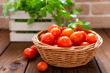 Fresh tomatoes in basket on wooden table closeup