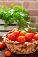 Fresh tomatoes in basket on wooden table closeup