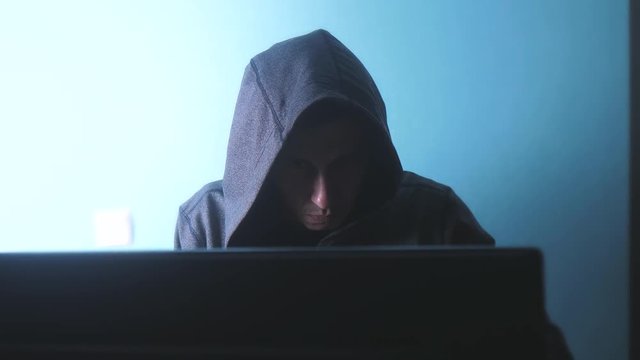 man hacker in the hood concept. unknown hacker criminal breaks into computer protection on the Internet passwords. male hacker penetrates into hack network protection web lifestyle phishing technology