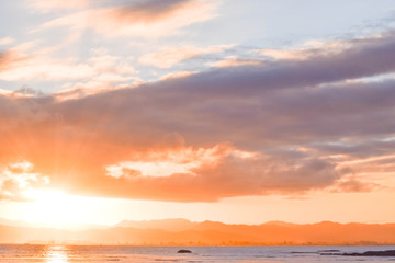 Fototapeta na wymiar The pale sunset colors the beach scene below in Gisborne, New Zealand.
