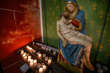 Trier / Germany - February 9 / 2019: Colored statue of mother mary and Jesus in front of candles in Saint Gangolf's church