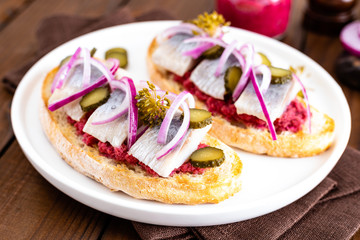 Delicious grilled sandwiches with herring, onion and beetroot sauce with horseradish on dark wooden rustic background. Danish cuisine