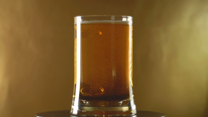 Beer glass octoberfest rotates on golden background.