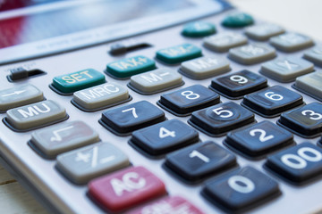 Calculator on white wooden background close-up.