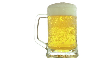 Beer is poured into a glass of foam leaking against white background