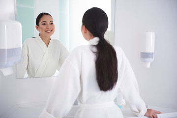 Happy asian lady look at mirror with satisfaction