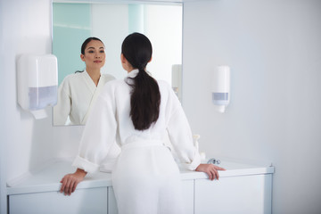 Fototapeta premium Asian lady look at mirror with satisfaction